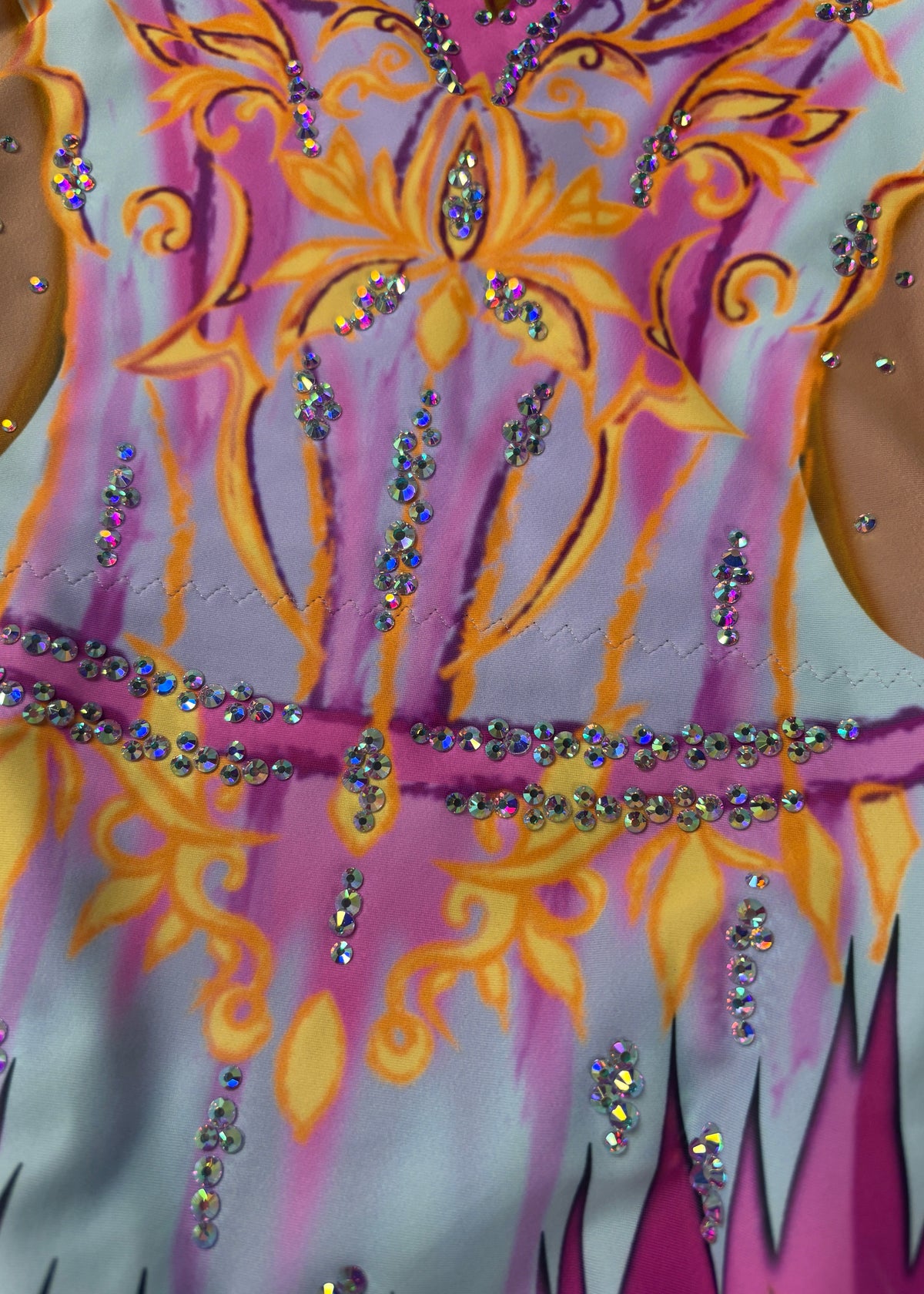 Detail des gelb-orangen Ornaments und der Kristalllinien auf himmelblauem und rosa Grund.