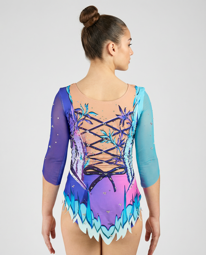 Maillot de gimnasia rítmica en degradado rosa-morado con mangas turquesa, pedrería y motivos florales creando un estilo delicado y luminoso.
Maillot rítmico turquesa y morado con degradados, pedrería y detalles florales que aportan un diseño elegante y fantasioso.
Espalda de maillot rítmico en tonos turquesa y morado con transparencias, pedrería y diseño floral con lazos impresos en un estilo mágico.