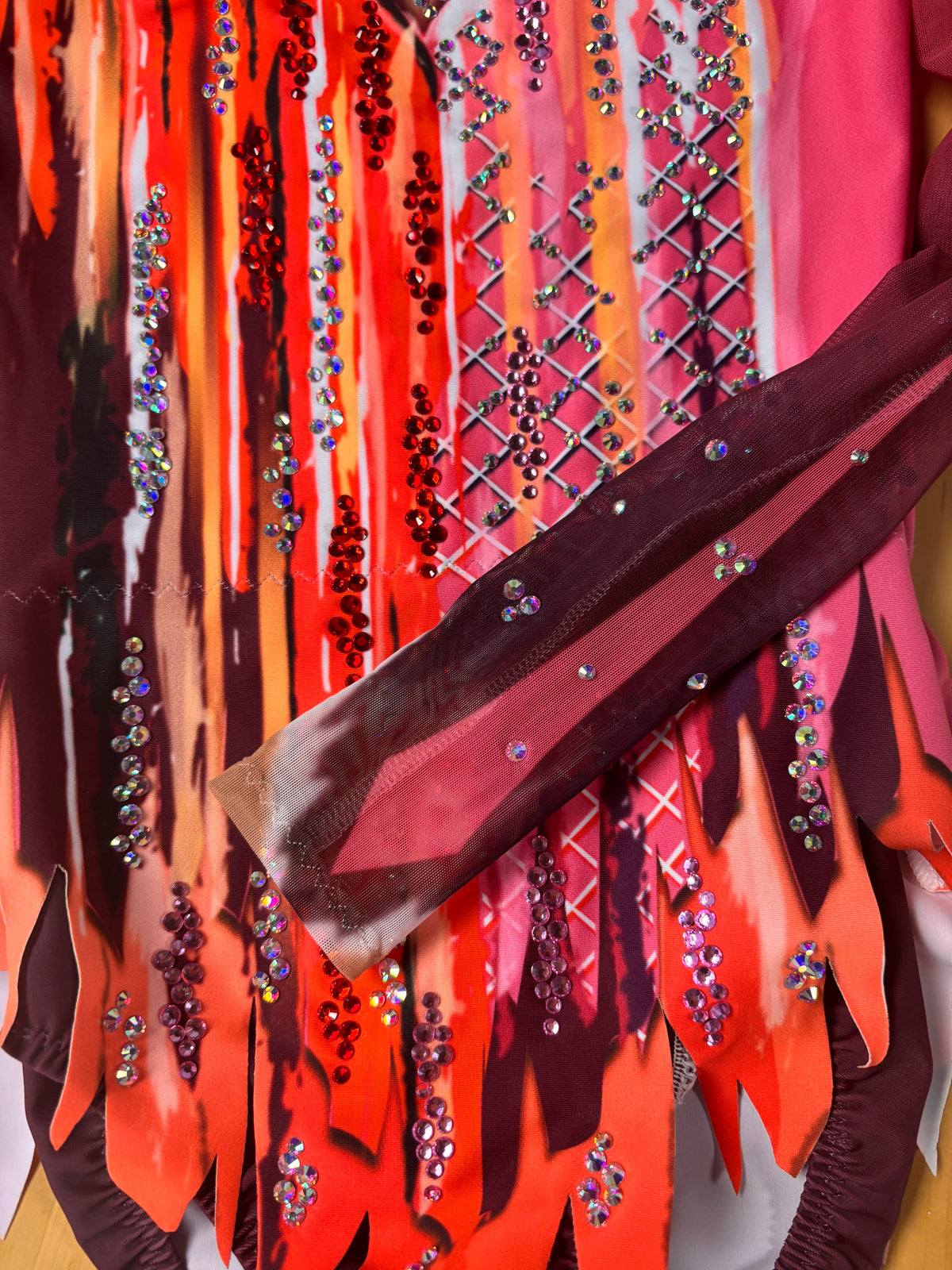 Detail des langen Ärmels und des spitzen Saums von Goya mit orangefarbenen und magentafarbenen Strichen und sichtbarem Strass.