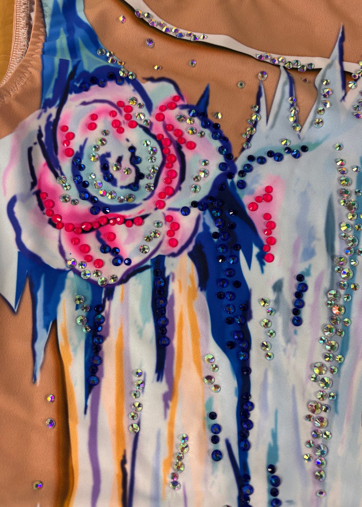 Detail der rosa-blauen Blüte und blauer, rosa und irisierender Verzierungen am Ausschnitt.